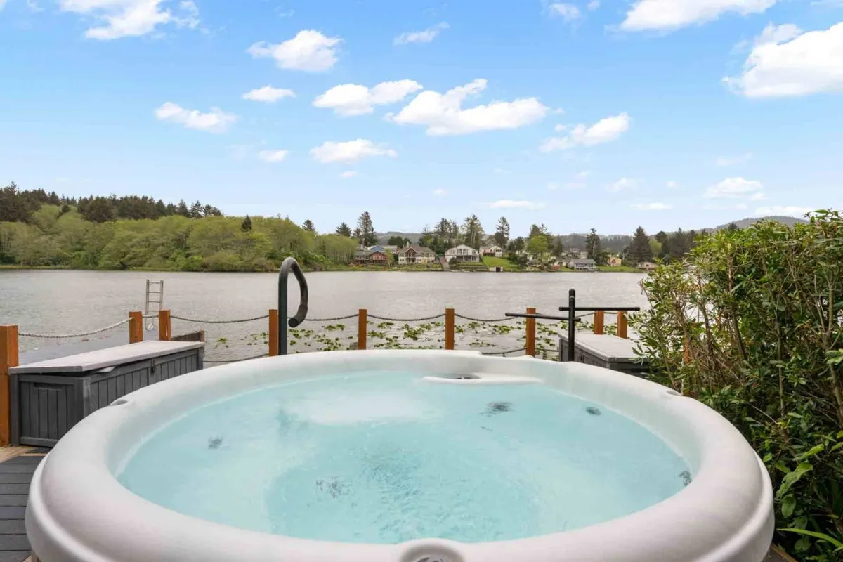 An inviting outdoor hot tub positioned to overlook the water, surrounded by natural greenery. The peaceful setting highlights both relaxation and the connection between comfort and nature, ideal for unwinding after lakeside adventures.