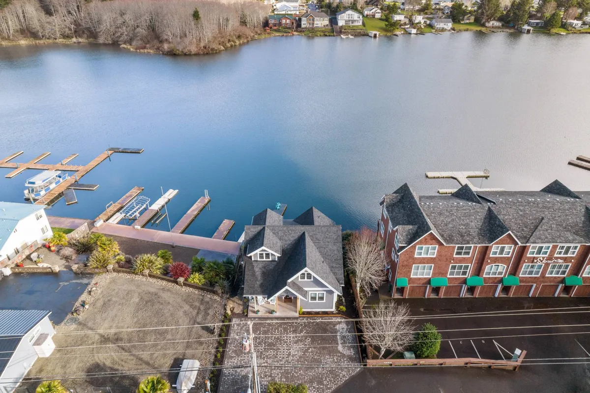 A panoramic view of the lake, marina, residential homes, and landscaped gardens, with a paved driveway inviting you to stroll or bike around. The tranquil water reflects the sky, and the area is ideal for boating, fishing, outdoor dining, or nature walks.