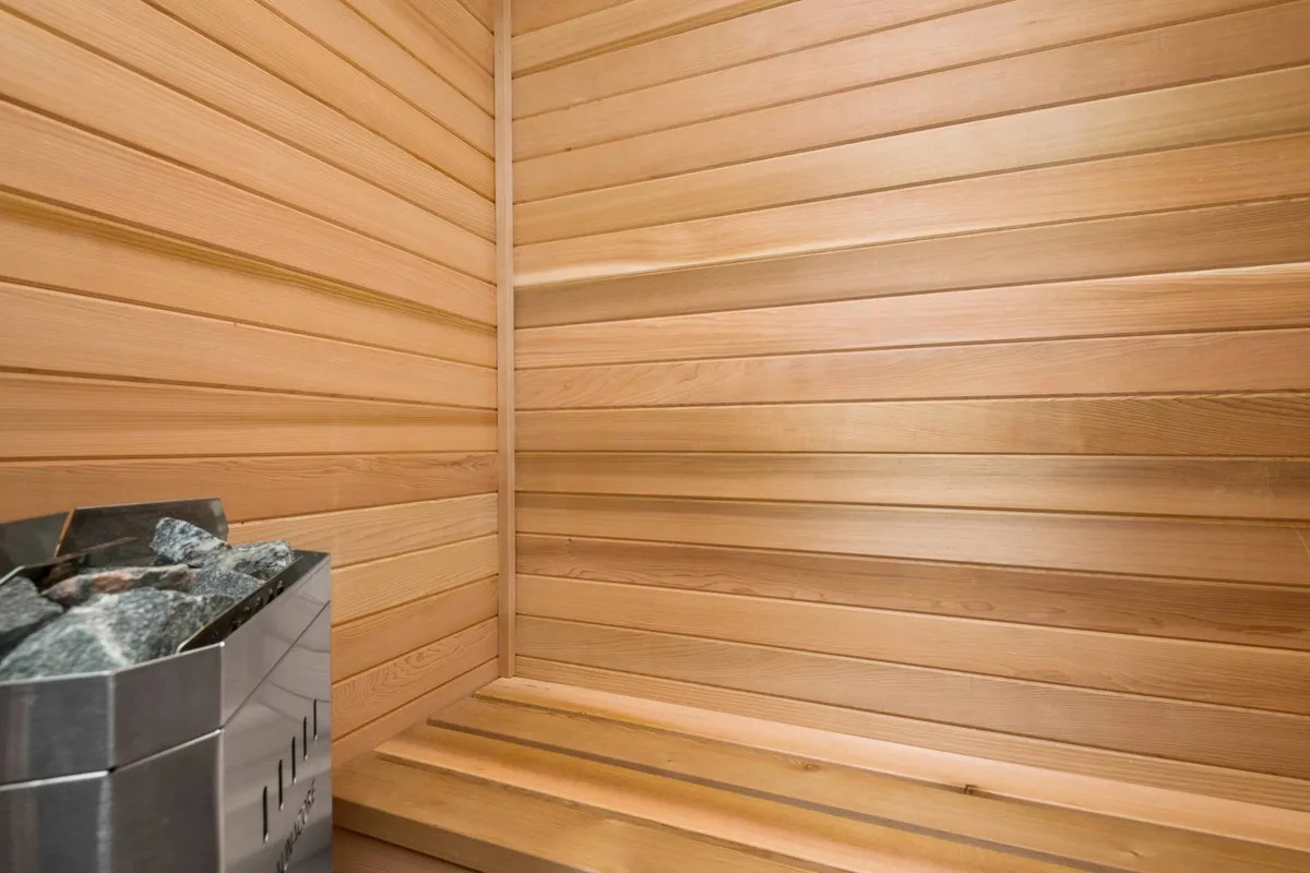 A tranquil sauna room with wooden paneling, a sauna heater, and bench seating. The mood is calming and rejuvenating, inviting guests to unwind after a day of fun.