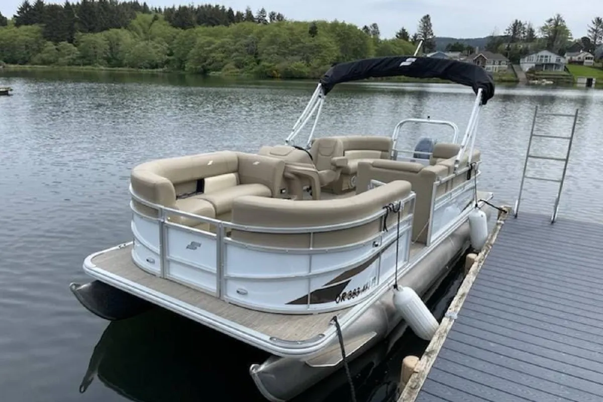 A tranquil exterior scene of a dock extending onto Devil’s Lake, featuring a pontoon boat moored at the dock and lush greenery surrounding the calm water. The setting invites boating, fishing, and social gatherings on the water.